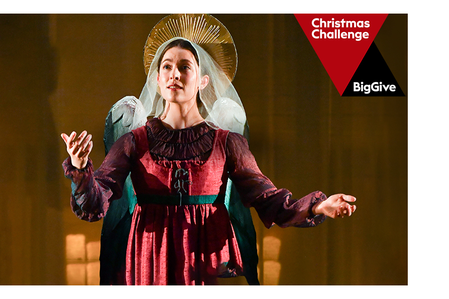 A female student wearing a historical costume with a veil and wings, performing on stage.
